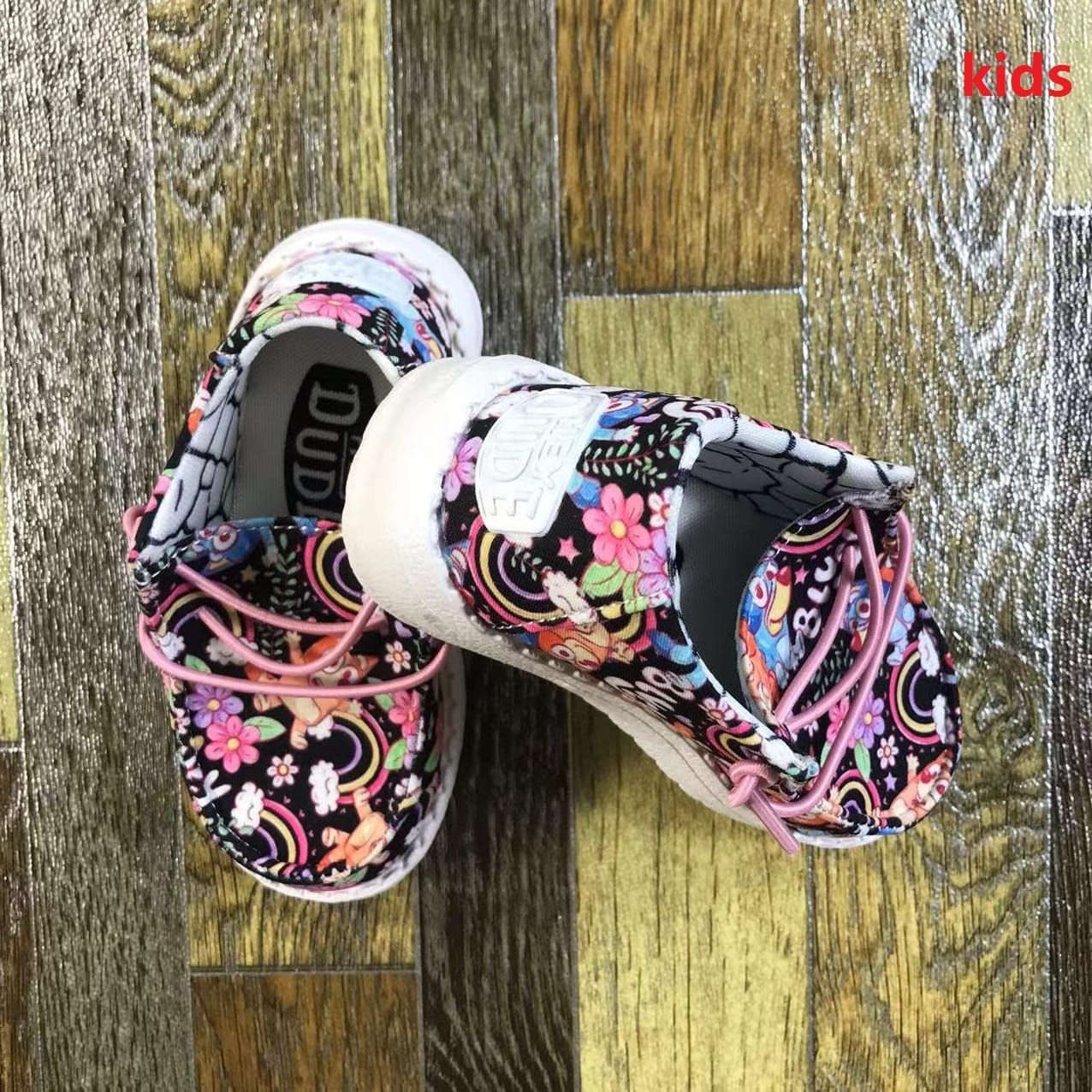 A pair of kids shoes are sitting on a wooden floor.