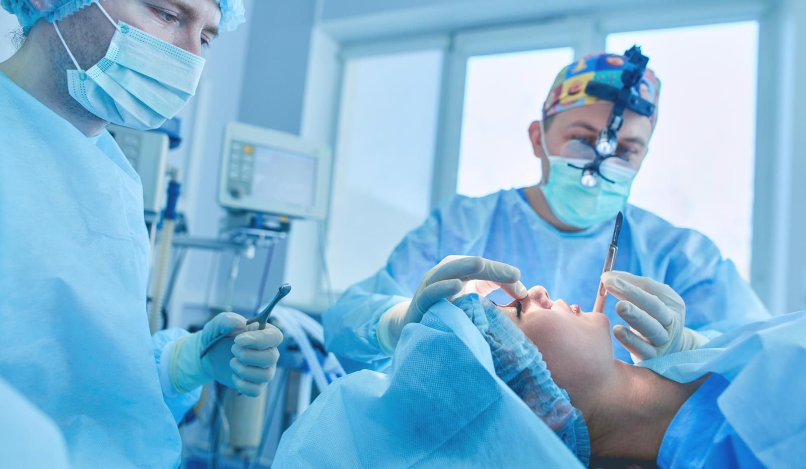 two surgeons are performing surgery on a patient with a monitor in the background