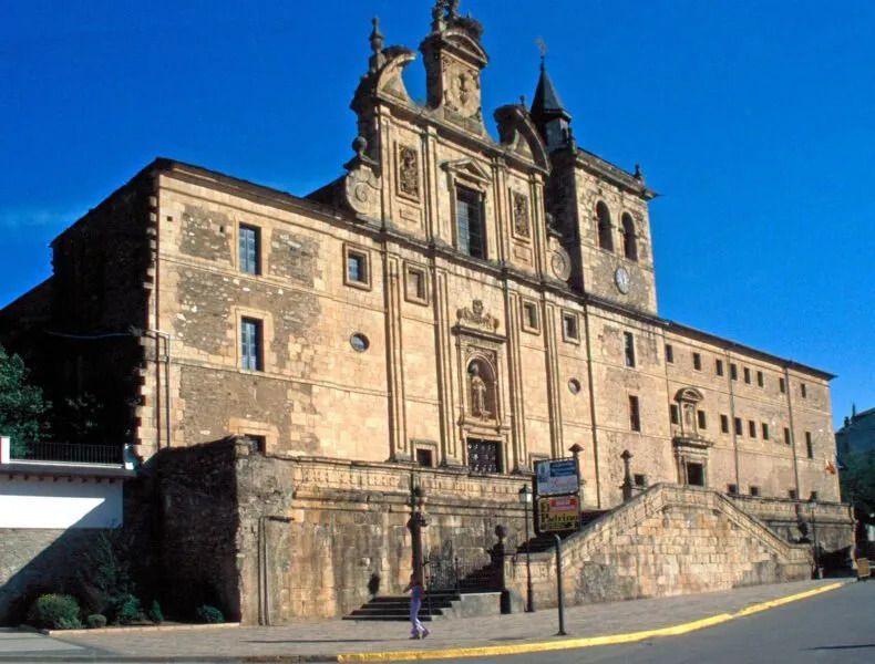 Stone building with ornate facade, stairs leading up, blue sky.