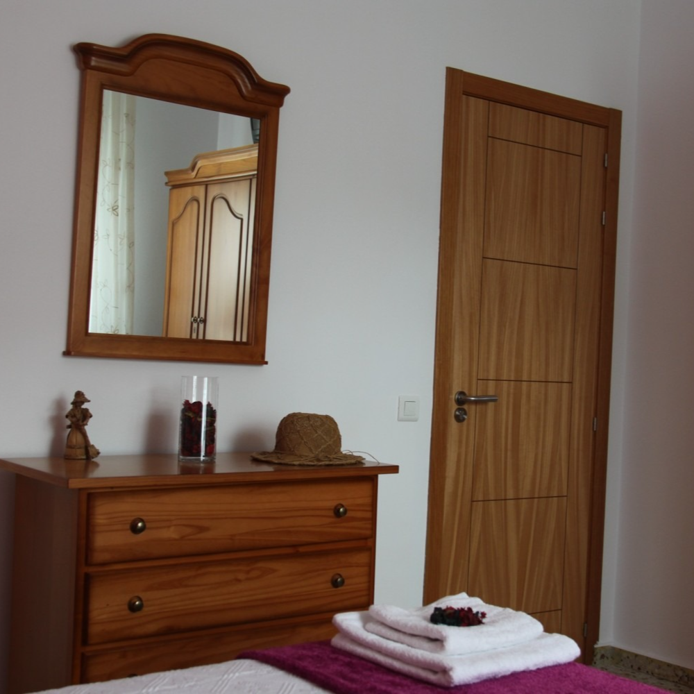 A bedroom with a dresser a mirror and a door