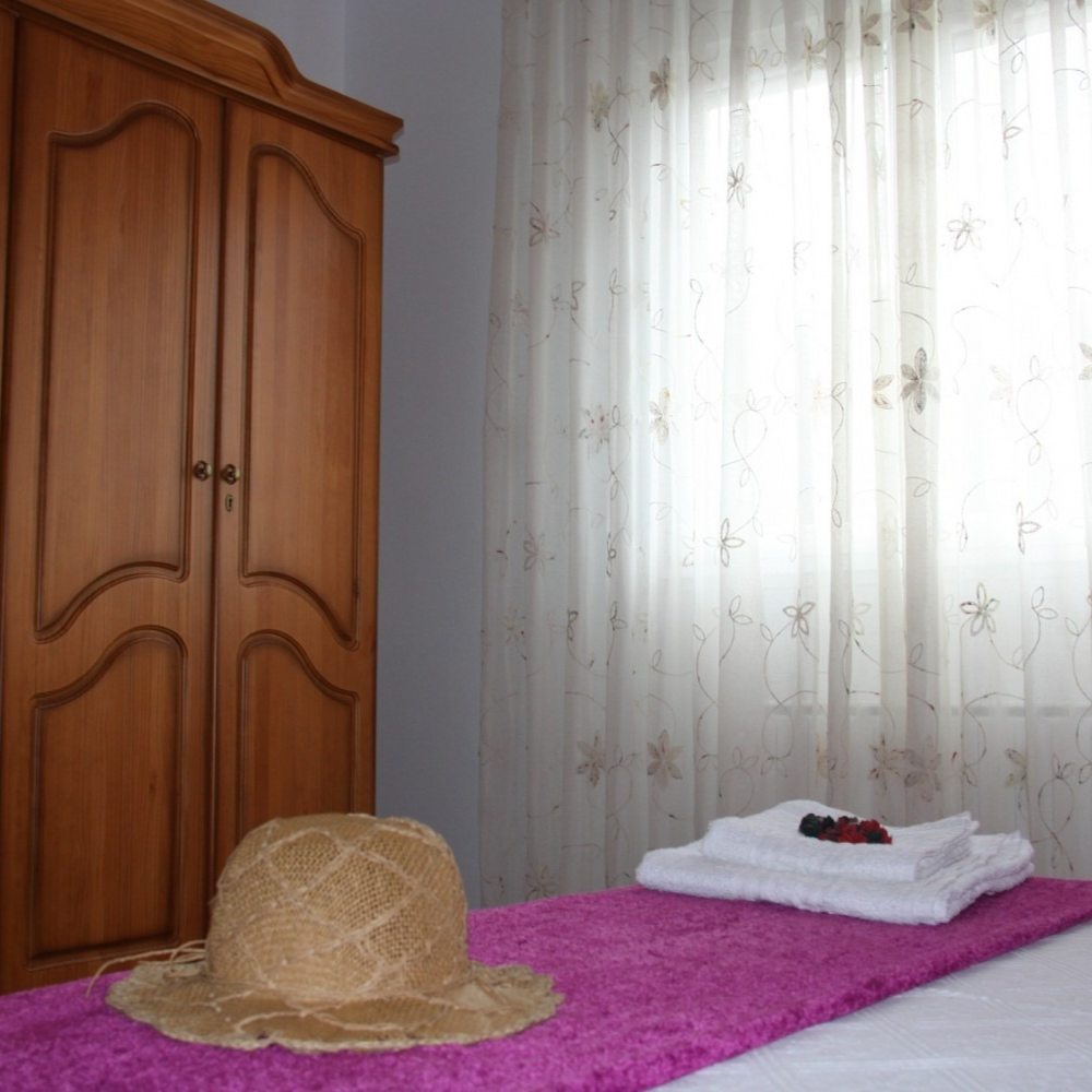 A straw hat sits on a bed next to a window