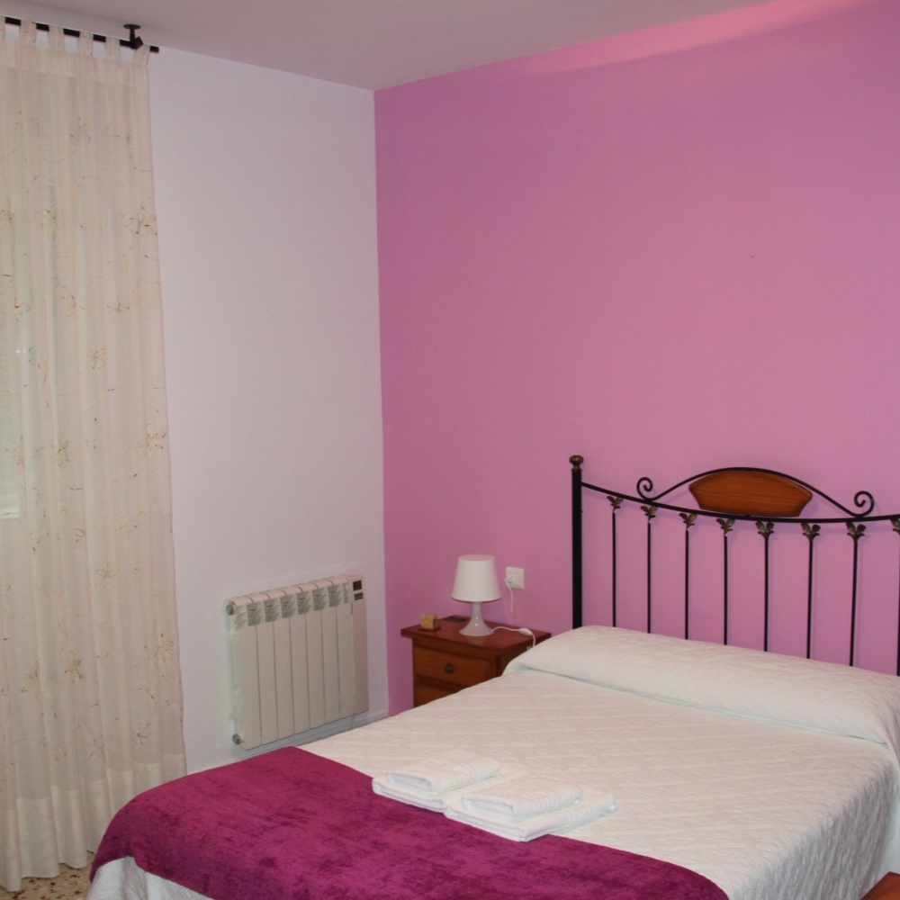 A bedroom with pink walls and a bed