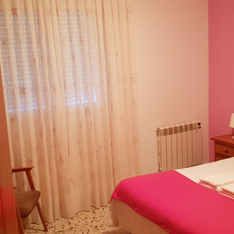 A bedroom with a bed a chair and a radiator