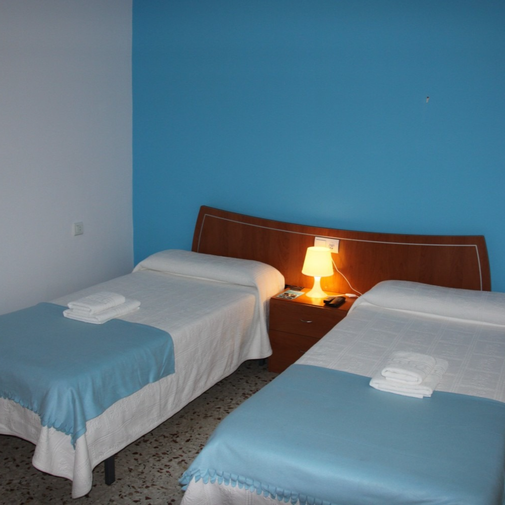 A bedroom with two beds and a blue wall