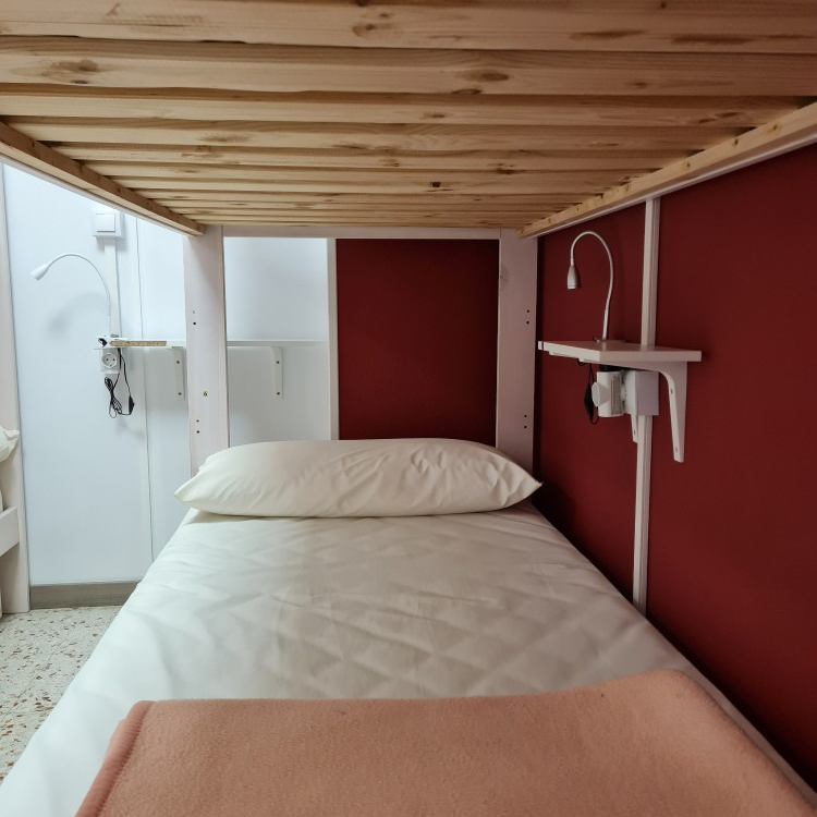 A bunk bed with white sheets and a pink blanket