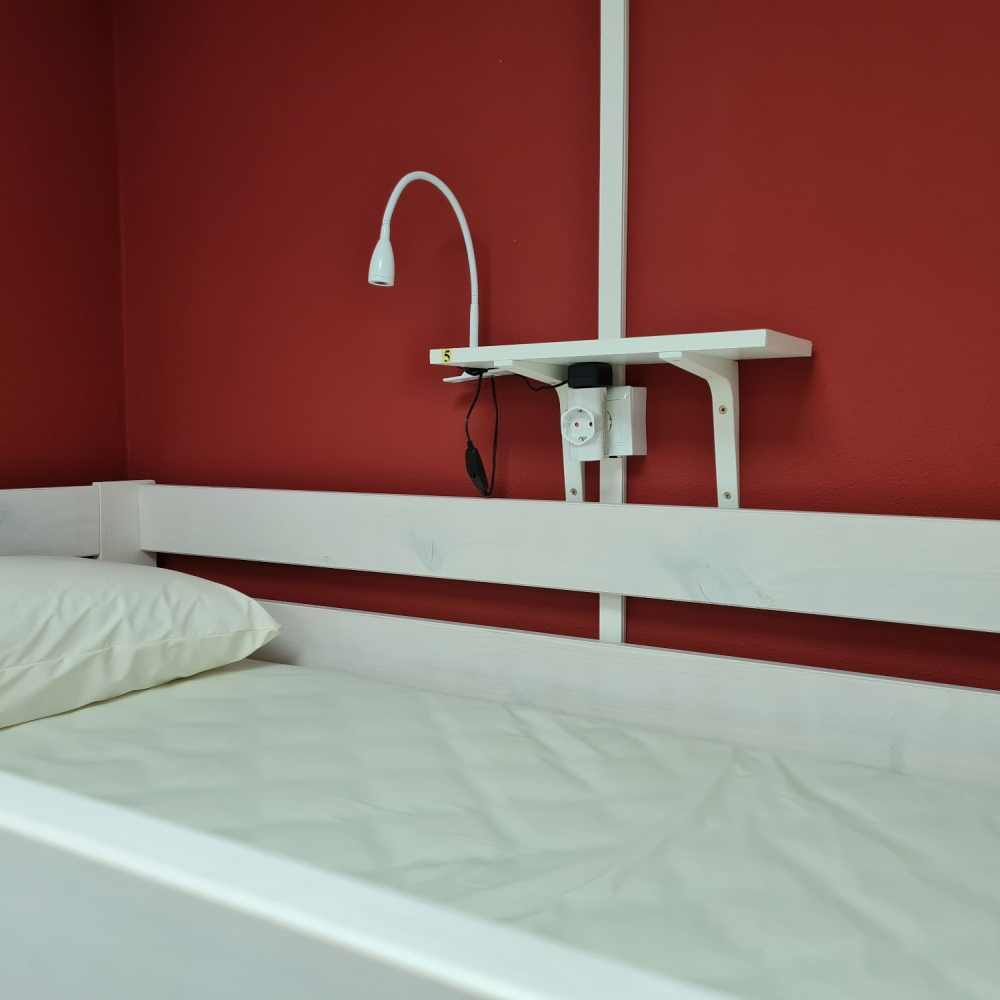 A bed with a red wall and a white headboard
