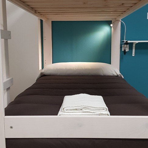 A bunk bed with a blue wall behind it