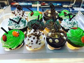 Assorted decorated cupcakes with green, white, and chocolate frosting in a bakery display case