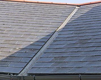 a close up of a roof with slate tiles and a gutter .