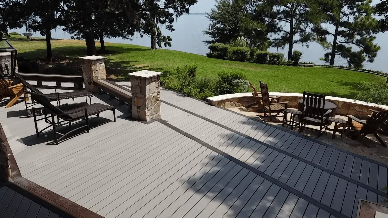 A deck with chairs and tables overlooking a lake