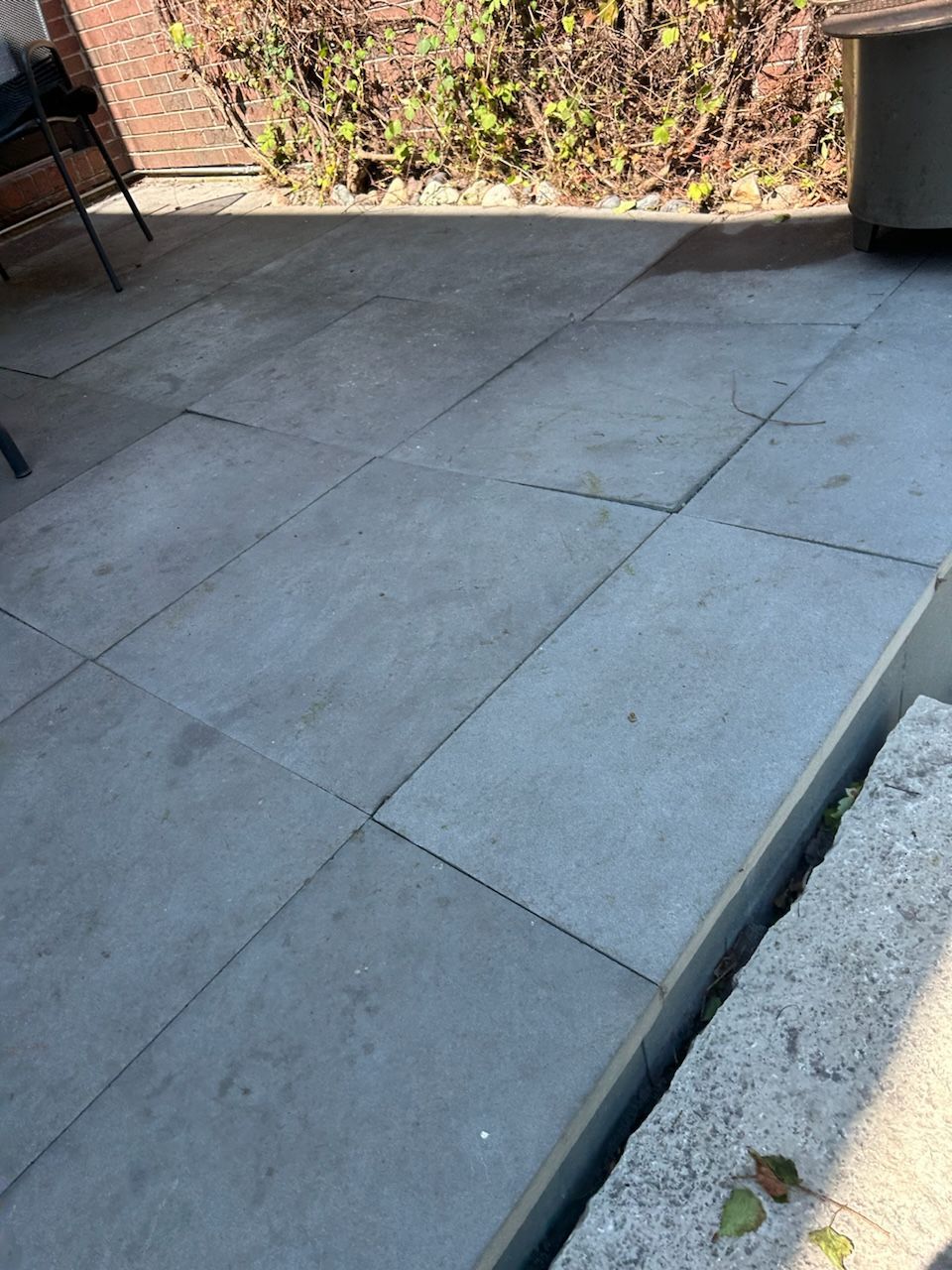A patio with a lot of tiles on it and a brick wall in the background.