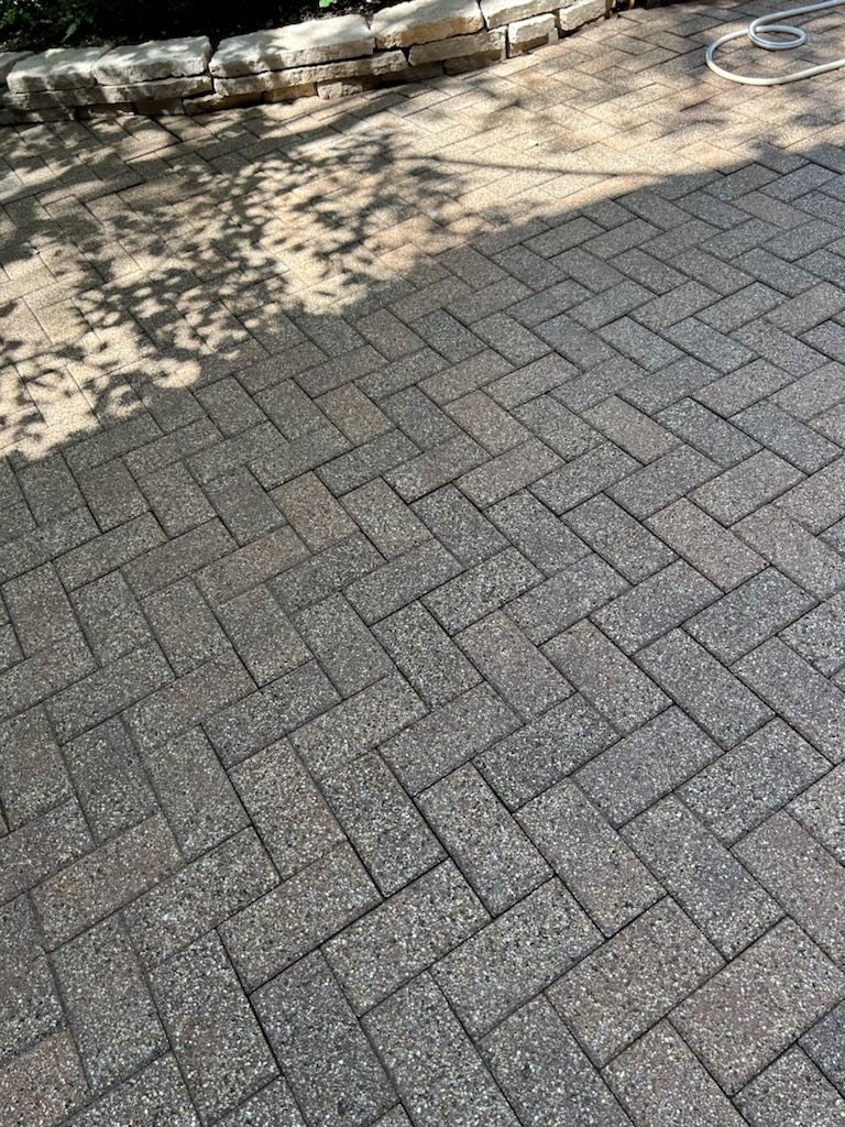 A close up of a brick patio with a hose on it.
