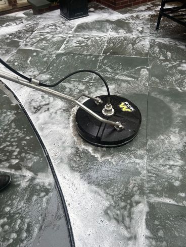 A person is cleaning a patio with a pressure washer.