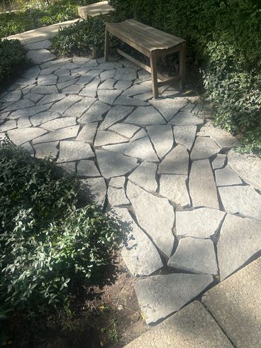 A wooden bench is sitting on a stone walkway.