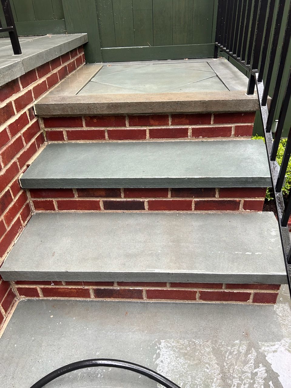 A set of stairs made of brick and concrete next to a railing.