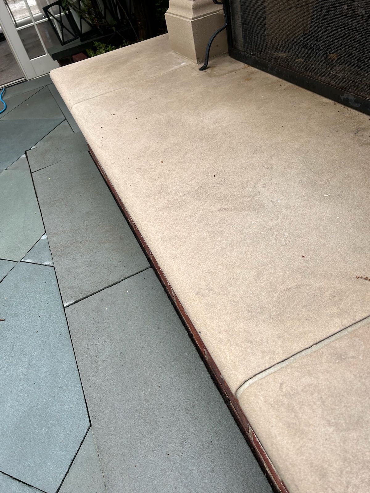 A concrete bench is sitting on top of a tiled floor.