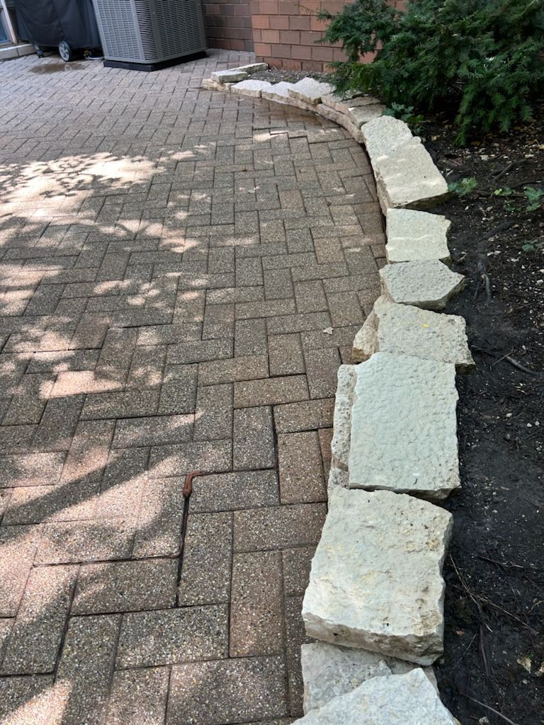 A brick walkway with a stone border and a brick wall in the background.