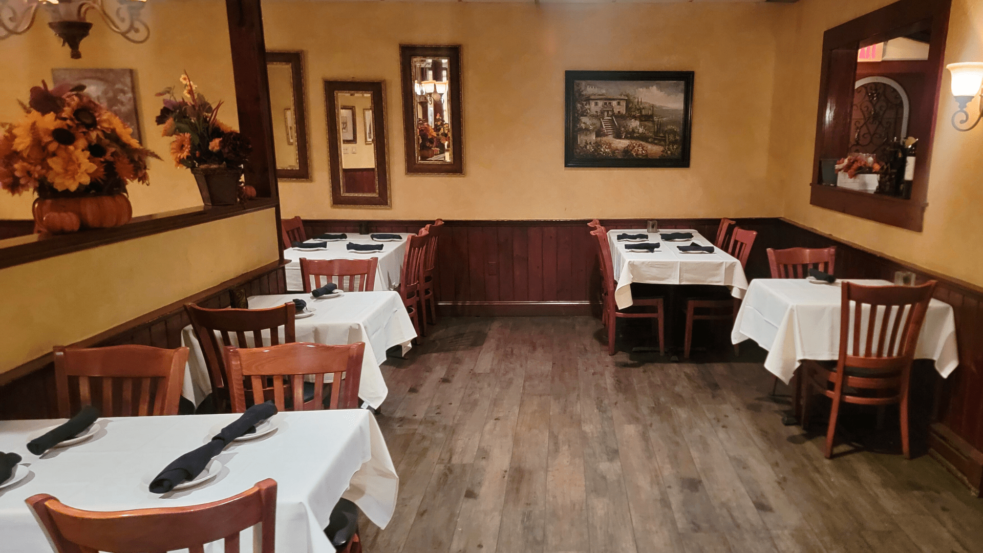 A restaurant with tables and chairs and a painting on the wall.
