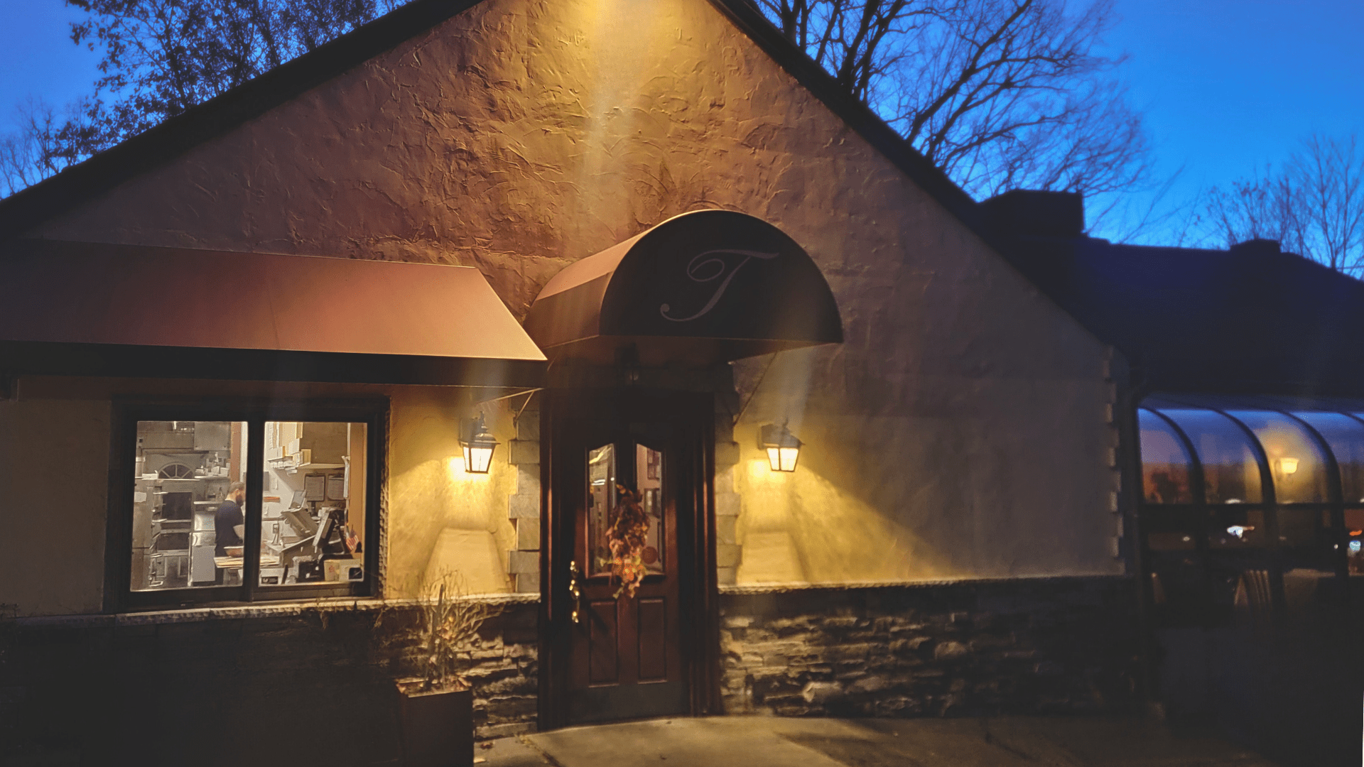 Tambascio's restaurant building with a canopy over the entrance is lit up at night.