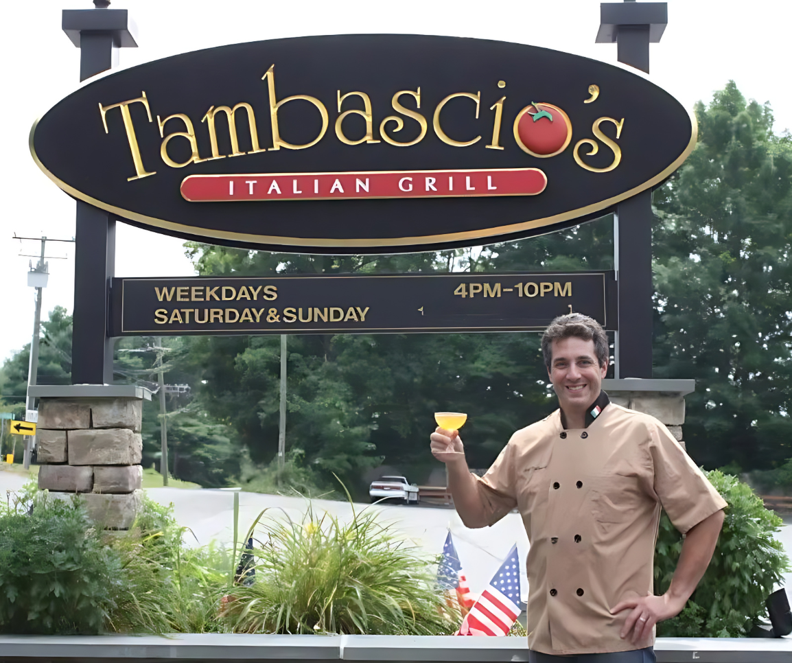 Owner John Tambascio stands in front of a sign for Tambascio 's Italian Grill