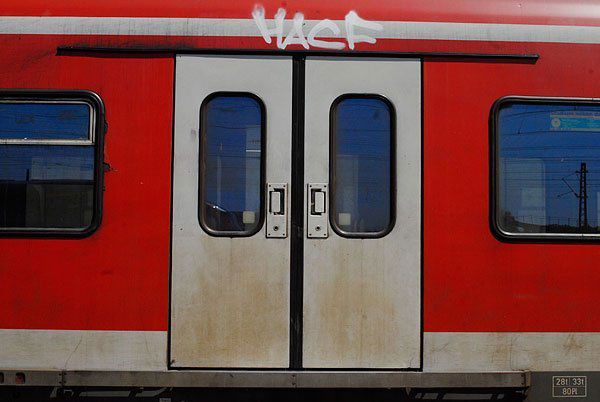 Ein rot-weißer Zug mit Graffiti an den Türen