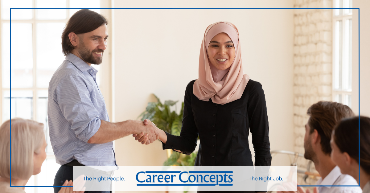 A man and woman shaking hands in front of a group