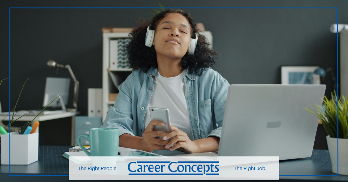Job candidate calming nerves while preparing for an interview with music, laptop, and phone at desk