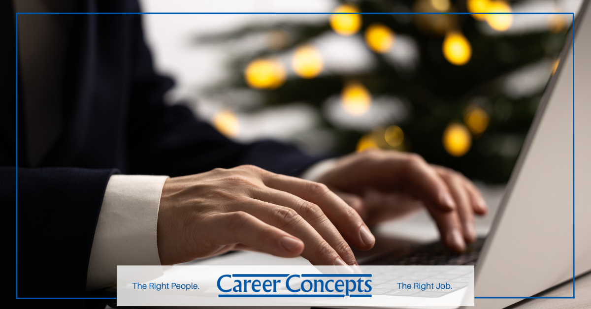 Professional employee working on laptop with Christmas tree in the background.