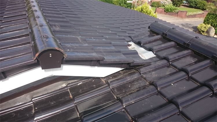 Eine Nahaufnahme eines schwarzen Ziegeldachs mit weißer Verzierung.