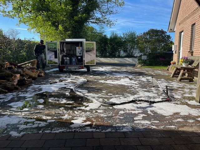 Ein weißer Lieferwagen steht in einer Einfahrt neben einem Backsteinhaus.