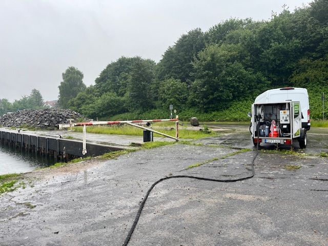 Ein weißer Lieferwagen steht auf einem Parkplatz neben einem Gewässer.