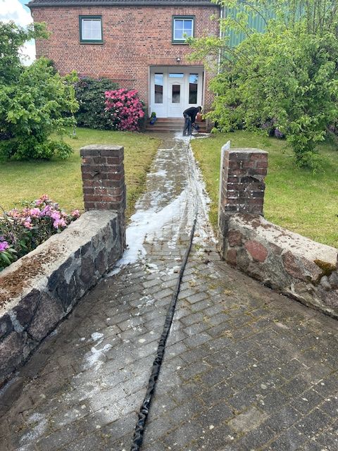 Ein Mann reinigt einen Ziegelweg vor einem Ziegelhaus.