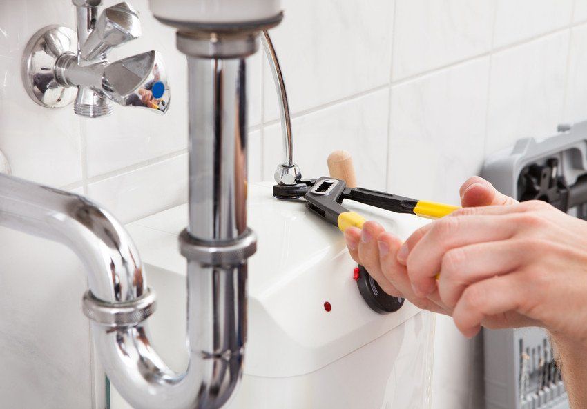 Portrait of male plumber fixing a sink in bathroom