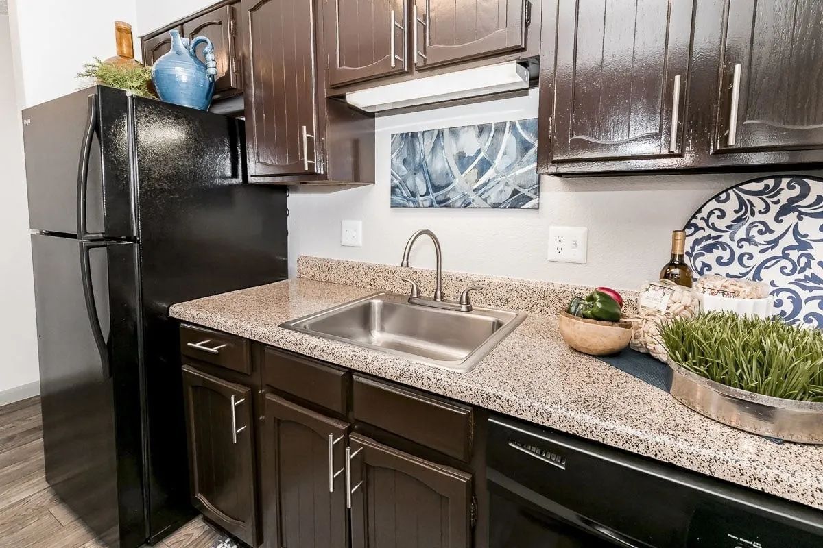 a kitchen with a sink and a black refrigerator