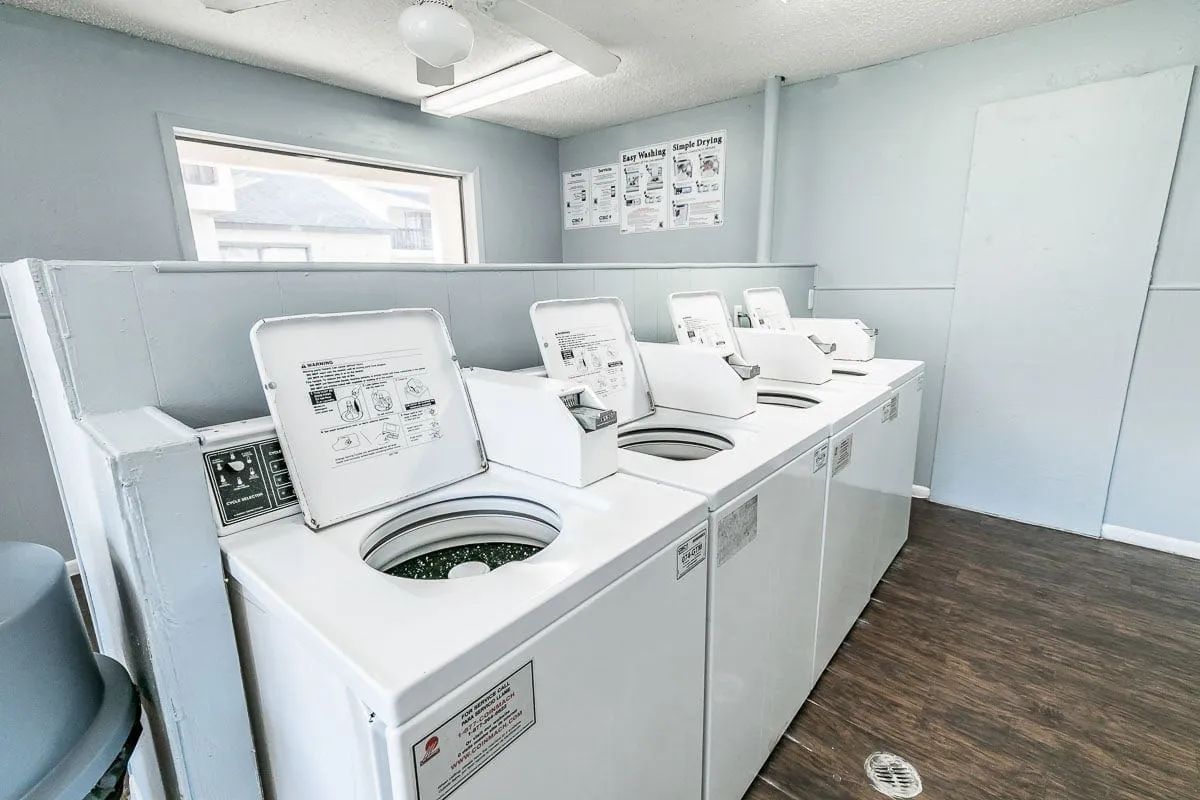 a row of white washers and dryers in a laundromat