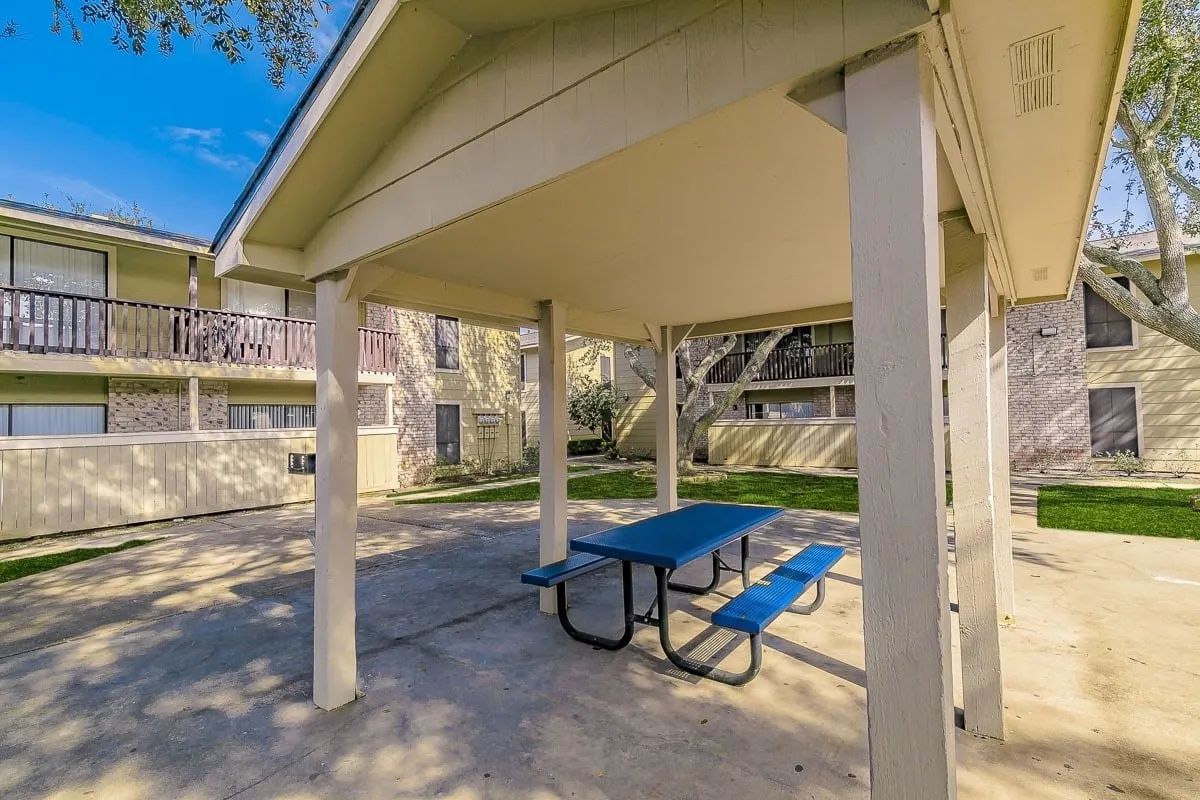 a blue picnic table under a covered area in front of a building