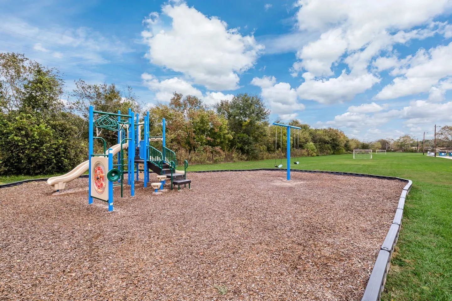 a playground with a slide and swings in the middle of a field