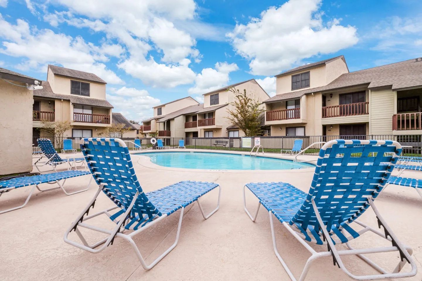 a swimming pool surrounded by lawn chairs and buildings