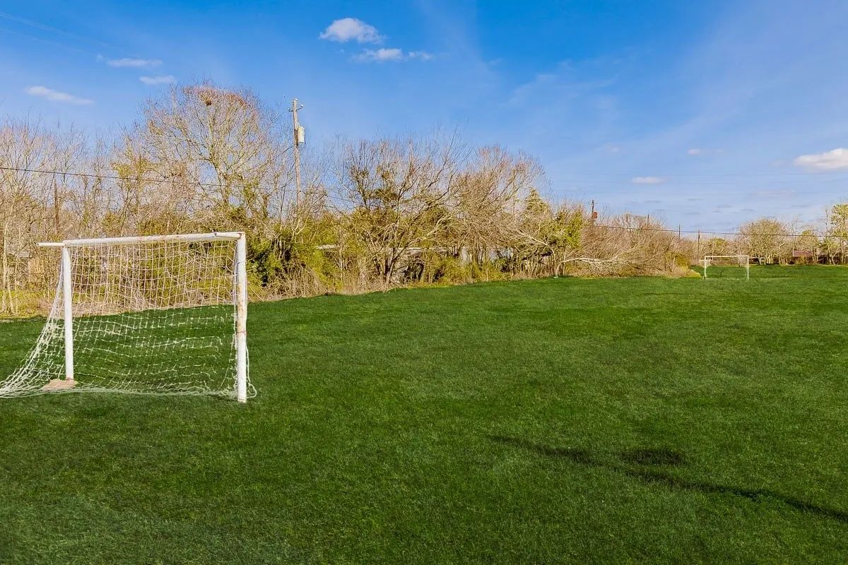a soccer goal in the middle of a field with trees in the background .