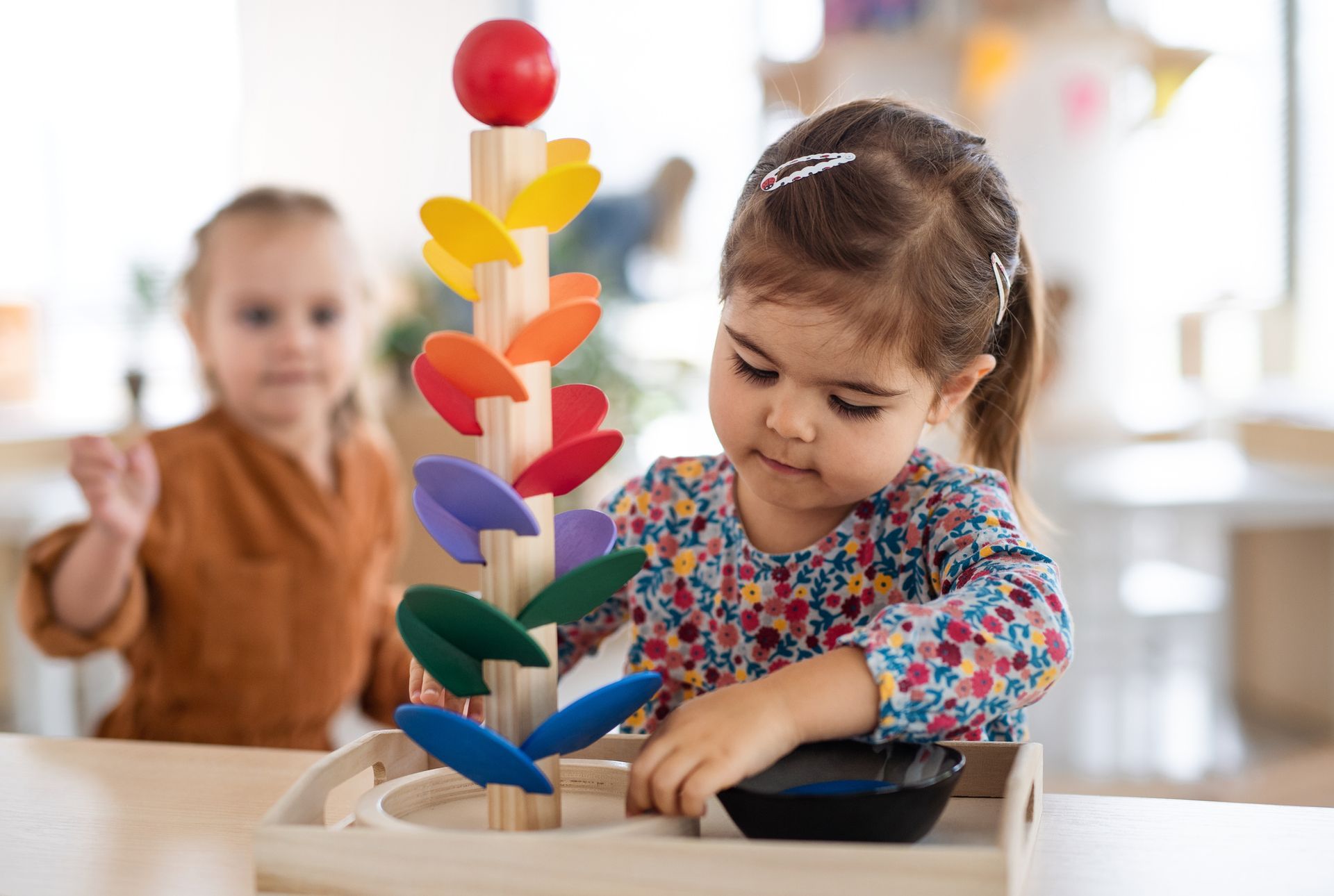 A little girl is playing with a wooden toy.