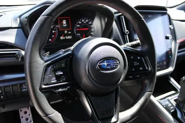 A close up of a subaru steering wheel in a car.