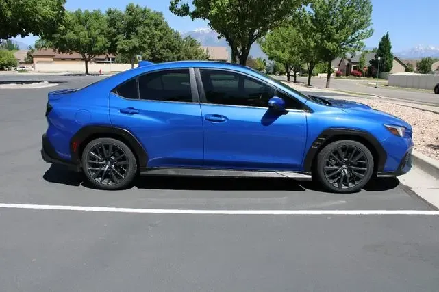 A blue subaru wrx sti is parked in a parking lot.