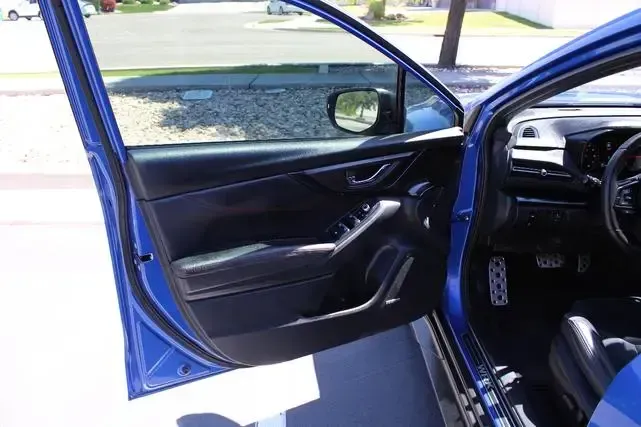 A blue car with its doors open is parked on the side of the road.