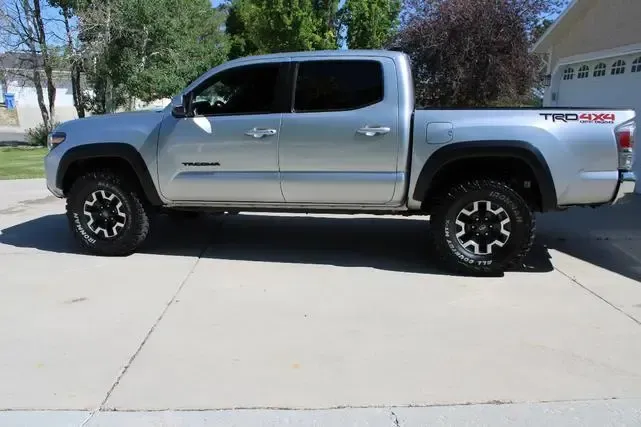 A silver truck is parked in a driveway next to a garage.