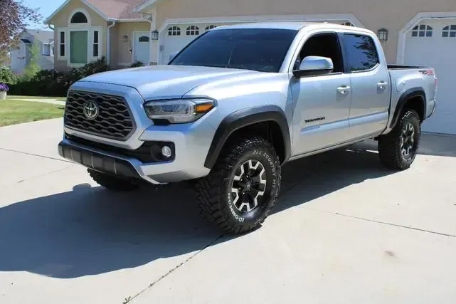 A silver toyota tacoma truck is parked in front of a house.