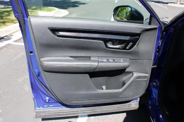 A blue car with the door open is parked on the side of the road.