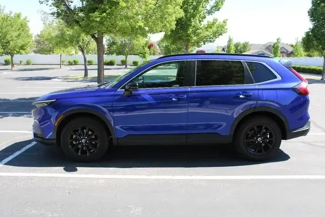 A blue suv is parked in a parking lot with trees in the background.