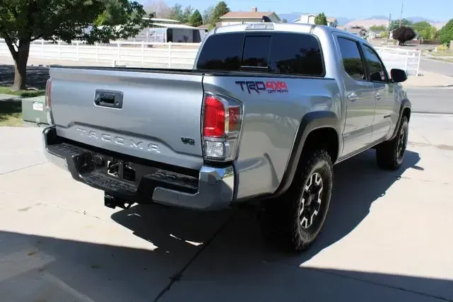 A silver toyota tacoma truck is parked on the side of the road.