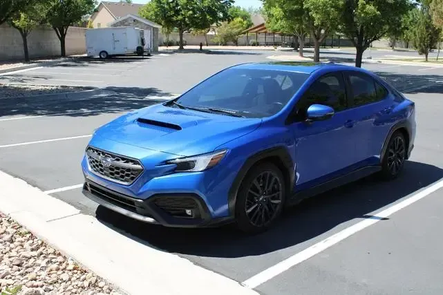 A blue subaru wrx sti is parked in a parking lot.