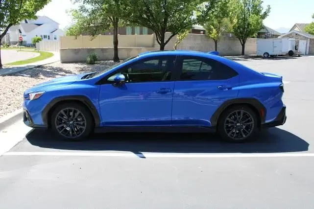 A blue subaru wrx sti is parked in a parking lot.